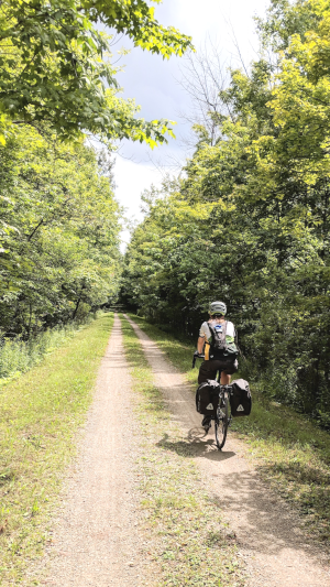 Photograph of Zachary Jacobi cycling down a lush trail on a long Ontario summer day.